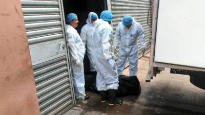 Médicos forenses trasladan los cadáveres a una fosa.