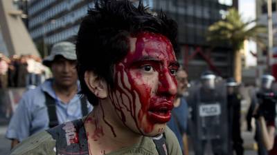 Una manifestante enmascarada que protesta contra la violencia de gÃ©nero se detiene con un letrero frente a los medios a la entrada de Palacio Nacional en Ciudad de MÃ©xico el viernes 14 de febrero de 2020. (AP Foto/Ginnette Riquelme)