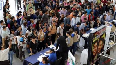 Hondureños entregando documentación en feria de empleo.