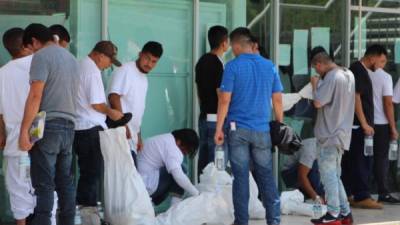 Migrantes deportados colocan sus pertenencias en bolsas blancas al cruzar por la garita Puente Nuevo, en el paso fronterizo de Matamoros (México). EFE/Abraham Pineda Jácome