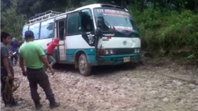 Los vecinos del lugar y hasta los propios pasajeros de esta unidad, ayudan a mover los vehículos que quedan atascados en la carretera. Foto Hernán Castro.