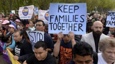 Varias personas se manifiestan mostrando pancartas en las que se puede leer 'Mantened a las familias unidas', 'Alto a las deportaciones' en contra de las deportaciones, detrás de un policía, a las afueras de la Casa Blanca en Washington DC, Estados Unidos, hoy, lunes 28 de abril del 2014. La administración Obama autorizó más de dos millones deportaciones a principios del presente mes de abril, según los medios de comunicación. EFE