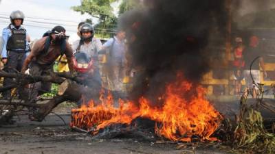 Un manifestante agita el fuego en el puente Quebrada Seca de El Progreso a Tela.