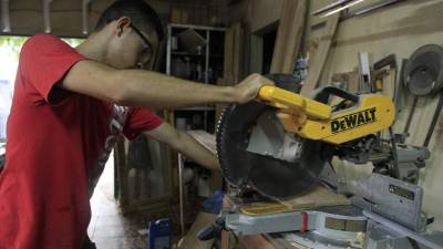 Un joven trabaja la madera en una microempresa de la ciudad.