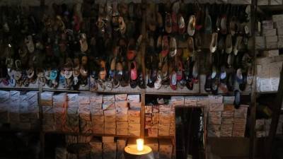 Vendedores encendieron una vela para iluminarse tras un apagón de la Enee adentro de una tienda de zapatos del mercado Medina. Foto: Yoseph Amaya.