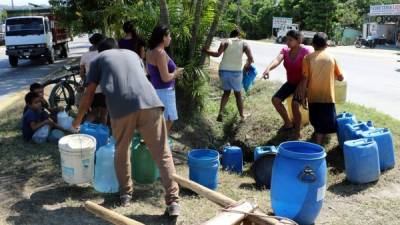 Niños, hombres y mujeres arriesgan sus vidas al cruzar el bulevar a Puerto Cortés para obtener un poco de agua. Fotos: Efraín Molina