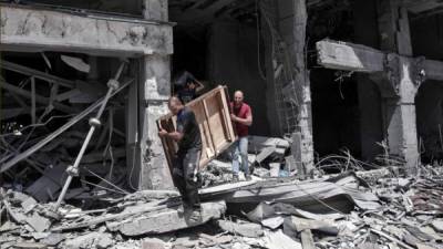 Hombres palestinos retiran artículos recuperables de la torre Al-Jawhara bombardeada en la ciudad de Gaza. Foto AFP