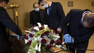 El propietario de la compañía de funerarias 'Palmero', Giampiero Palmero (2º L), revisa a los trabajadores de su compañía mientras colocan el ataúd de una víctima de COVID-19 antes de un funeral. Foto AFP