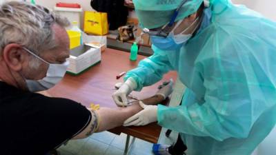 Un miembro del personal médico recolecta muestras de sangre de un residente para detectar el COVID-19 (nuevo coronavirus) en el pabellón deportivo de la pequeña ciudad de Robbio. Foto AFP