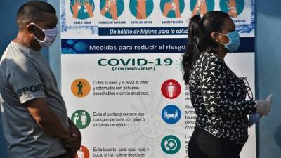 Las personas usan máscaras faciales contra la propagación del coronavirus mientras mantienen la distancia al hacer cola para ingresar al Instituto Hondureño de Seguridad Social en Tegucigalpa. Foto AFP