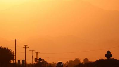 Los vehículos se ven por encima de un 'espejismo de carretera' causado por una fina capa de aire caliente sobre la calzada. Foto AFP