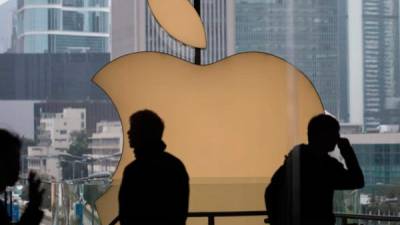 Clientes caminan junto al logotipo de Apple en la tienda Apple.