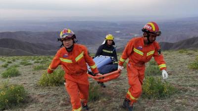 Rescatistas llevando equipo mientras buscan corredores que competían en una carrera de montaña cuando el clima extremo golpeó el área. Foto AFP
