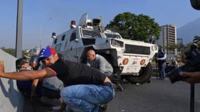 Los venezolanos se protegen durante los enfrentamientos con las fuerzas de seguridad en Caracas el 30 de abril de 2019.