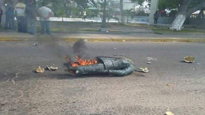 Luego de derribar la estatuta de Chávez, los manifestantes la prendieron en fuego.