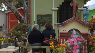 Dos mujeres reflexionan frente al mausoléo donde descansan los restos de sus familiares en México durante el festejo del Día de los Muertos.