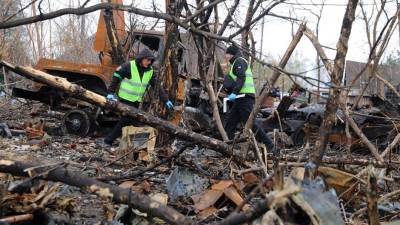 Investigadores forenses de la Policía ucraniana examinan un área con vehículos militares rusos quemados destruidos durante los combates.