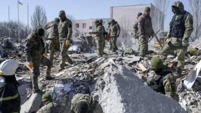 Soldados ucranianos buscan cuerpos entre los escombros de la escuela militar alcanzada por cohetes rusos el día anterior, en Mykolaiv.