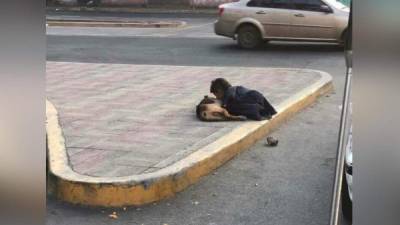 El menor hondureño cuando daba un beso al perro con el que vivía en las calles de Tegucigalpa.