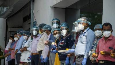 El personal médico espera en fila para animar y duchar los pétalos de las flores mientras los pacientes con coronavirus recuperados salen de un hospital privado. Foto AFP