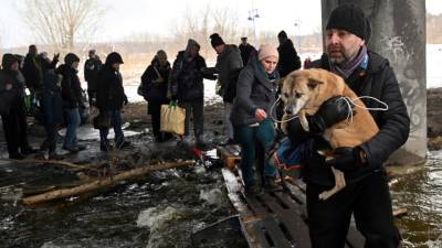 Un hombre carga un perro para cruzar un puente destruido mientras evacua la ciudad de Irpin, al noroeste de Kiev.