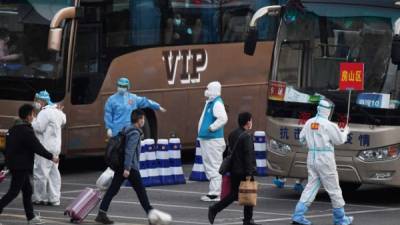 Personas caminan rumbo a un autobús en la capital china. Foto: AFP