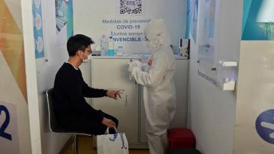 Un trabajador de la salud mide el nivel de oxígeno en sangre de un pasajero, en el aeropuerto internacional Benito Juárez de la Ciudad de México.