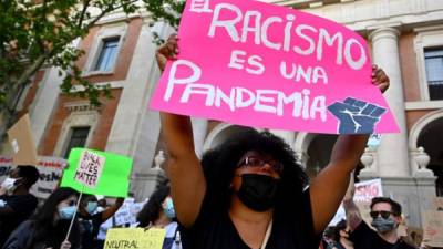 Un manifestante sostiene una pancarta que dice 'El racismo es una pandemia' en Madrid. Foto AFP