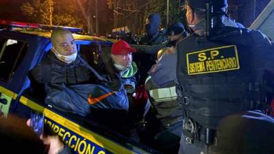 Miembros de la pandilla 18 en la parte trasera de un camión y frente al Centro Preventivo para Hombres mientras son escoltados por guardias. Foto AFP