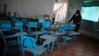 Ana Cristina González, maestra de la escuela Salvador Corleto, fue registrada al ordenar unos libros en un salón vacío durante la suspensión de clases por la pandemia en la aldea de Zuntule, al oriente de Tegucigalpa. Foto EFE