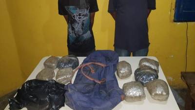 Momento en que las autoridades mostraban la evidencia decomisada a los dos sujetos.