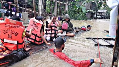 Prsonal de la guardia costera evacuando a los residentes locales de sus hogares inundados en una balsa improvisada en la ciudad de Panitan, provincia de Capiz.