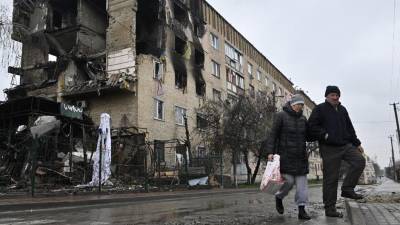 Los peatones pasan frente a un edificio residencial dañado en el pueblo de Gostomel, cerca de Kiev.