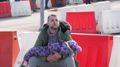 Un hombre ucraniano con un niño espera a su esposa mientras cruzan la frontera a Polonia.