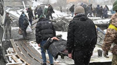 La gente lleva a una mujer herida durante la evacuación de civiles de la ciudad de Irpin.