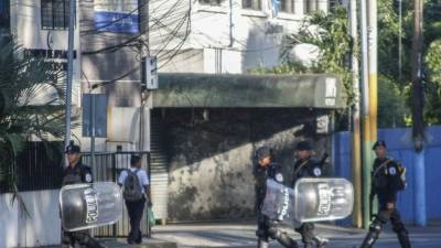 Policías caminan frente a la televisora 100 % Noticias. AFP