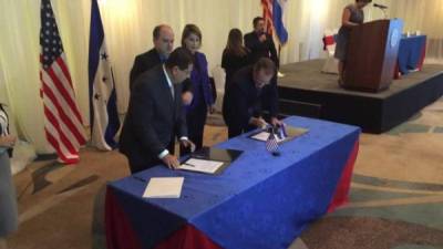 El coordinador general del Gobierno de Honduras, Jorge Ramón Hernández Alcerro y el Embajador de EUA, James Nealon, estampan su firma en un documento oficial.