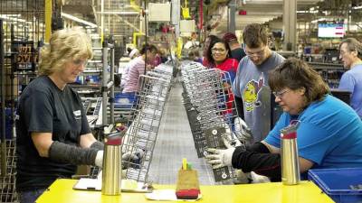 Los robots colaborativos trabajan en partes mientras los empleados arman lavavajillas en una línea de ensamblaje de Whirlpool en Findlay, Ohio.