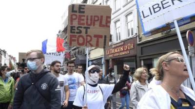 Un hombre sostiene una pancarta 'La gente es fuerte' durante una manifestación, parte de un día nacional de protesta contra el pase de salud obligatorio para acceder a la mayor parte del espacio público. Foto AFP