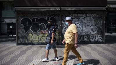 Dos personas pasan frente a un quiosco cerrado en el bulevar Ramblas en el centro de Barcelona. Foto AFP