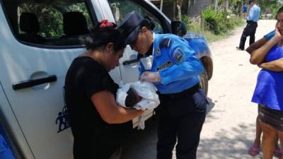 Una de las agentes policiales revisa al recién nacido en brazos de la persona que lo rescató.
