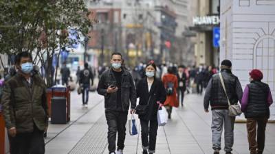 Una pareja camina por una calle comercial en Shanghai. Foto AFP