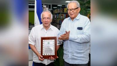 Julio Escoto recibiendo la placa de manos de Juan Ramón Martínez.