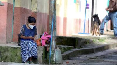 Una mujer descansa en una acera hoy, en el municipio de Valle de Ángeles (Honduras).