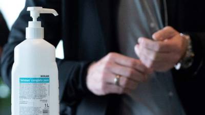 Un periodista se acerca a una botella de desinfectante que se proporciona a los visitantes para protegerse de una infección con el coronavirus SARS-CoV-2 en la Cancillería de Berlín, Alemania.