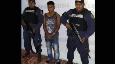 El joven es custodiado por dos elementos de la Policía Nacional de Honduras.