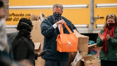 El alcalde de la ciudad de Nueva York, Bill de Blasio, sostiene una bolsa de productos empaquetados en un estante de alimentos. Foto: AFP