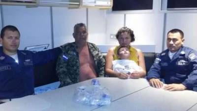 Dos agentes de la Naval rodean a Luis Alonso Cardona (abuelo), Kimberly Pacheco (madre) y el pequeño Ángel Pacheco, de años, quienes fueron rescatados en alta mar en Islas de la Bahía.