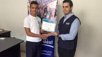 Momento en que Gerson, izquierda, recibe un reconocimiento en el programa de becas 20/20.