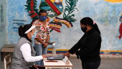 Una mujer con máscara vota en un colegio electoral de una escuela de Caracas durante las elecciones legislativas de Venezuela. Foto AFP